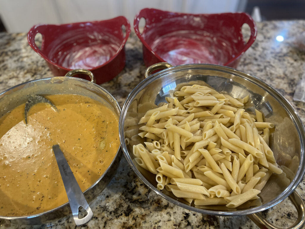 pasta in one bowl and an orange sauce in another