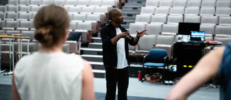 a male instructor addressing students while standing on the stage