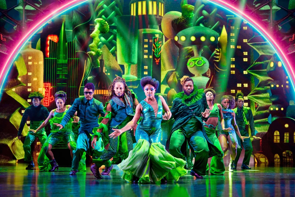 Nine green-garbed dancers form a V facing out to the audience as they work through their hips in unison.